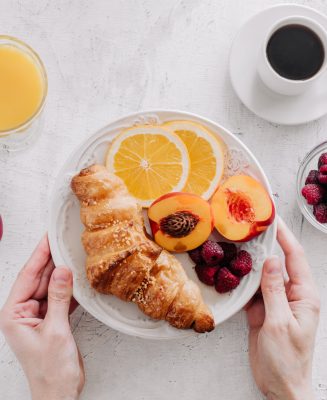 Breakfast with croissants, a cup of coffee, raspberries and orange juice top view